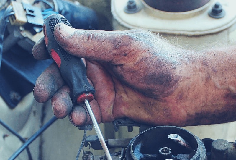 Hand holding a screwdriver repairing a portable generator